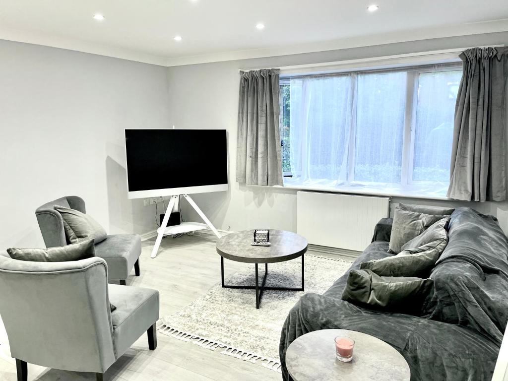 uma sala de estar com um sofá e cadeiras e uma televisão em Lovely 1 bed apartment, 15mins from Central London em Londres
