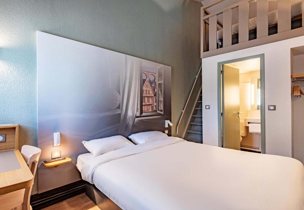 Un dormitorio con una gran cama blanca y una escalera. en B&B HOTEL Morlaix, en Saint-Martin-des-Champs