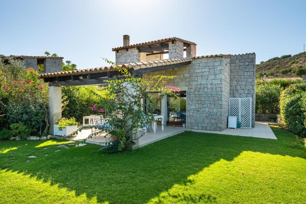 a garden with a stone house with a lawn at Villa Bouganville Cala Sinzias in Castiadas