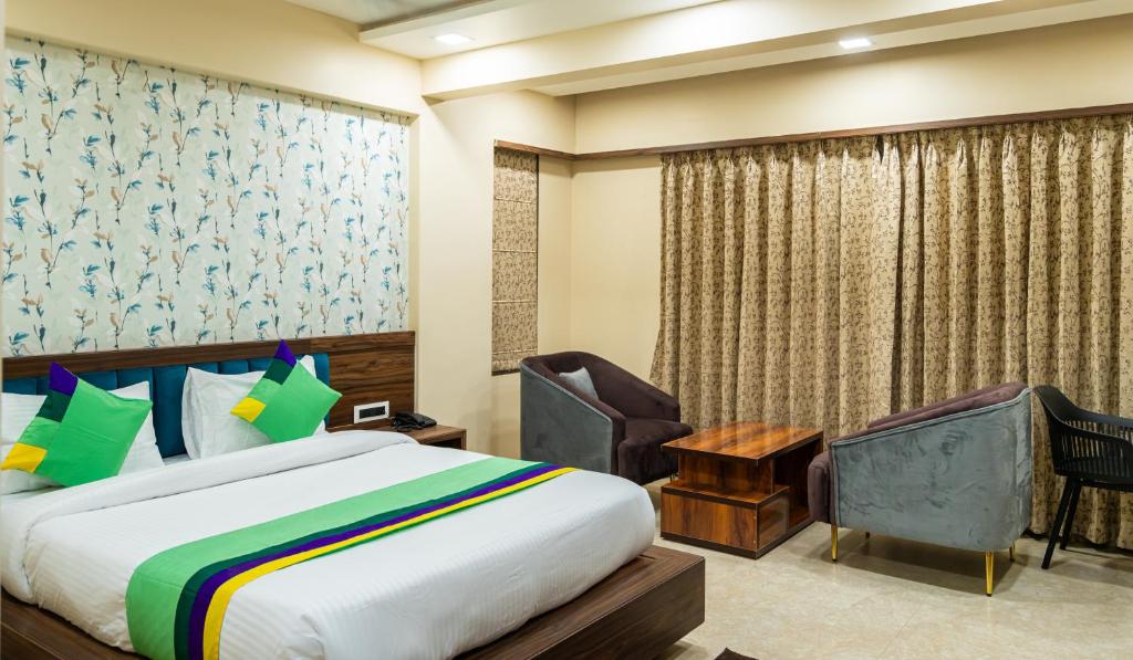 a hotel room with a bed and a chair at Treebo Trend Lemon Wood Suites in Pune