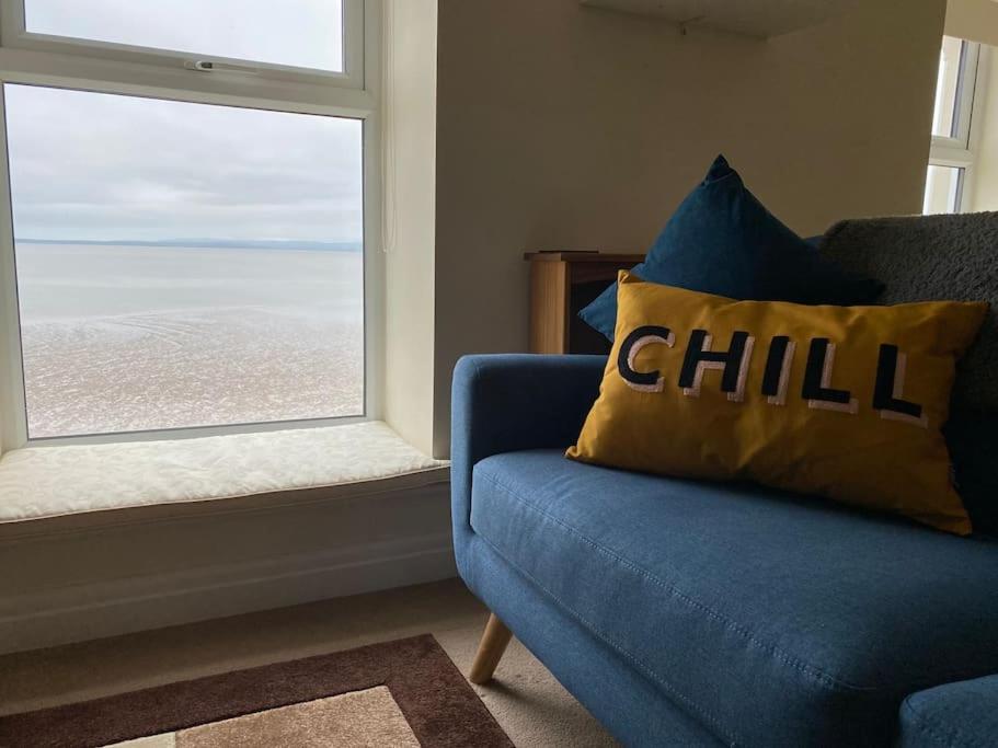 um sofá azul numa sala de estar com uma janela em Shore Enough - Morecambe Sea Front Apartment em Heysham