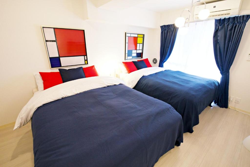 twee bedden in een slaapkamer met blauw en rood bij ダイトービル304 in Tokyo