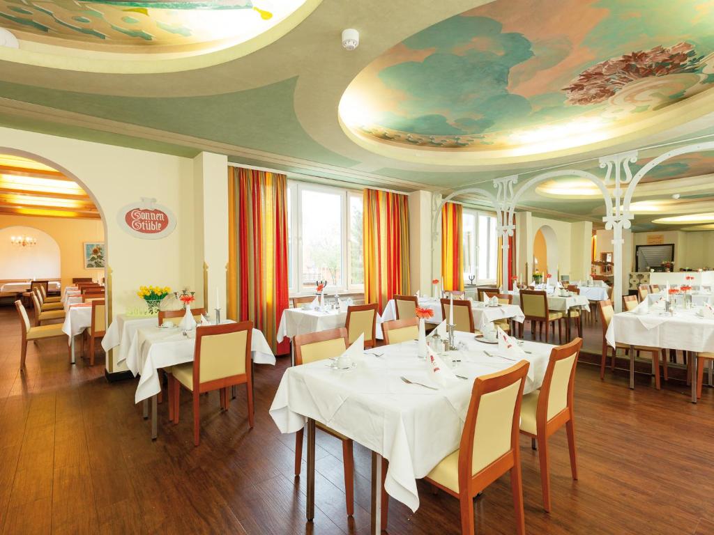 a restaurant with white tables and chairs and a ceiling at Morada Hotel Bad Wörishofen in Bad Wörishofen
