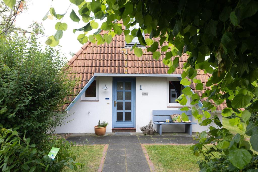 uma pequena casa branca com uma porta azul em OT 1 - Strandvogt 3 Komfort em Dorum Neufeld