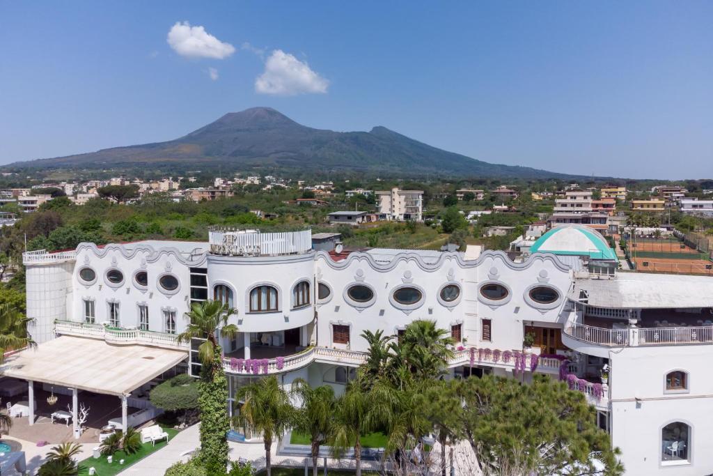 a white building with a mountain in the background at Hotel Imperiale in Terzigno