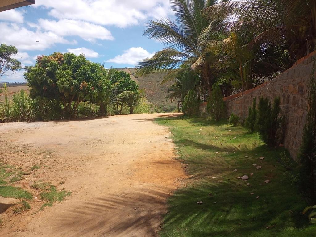 un camino de tierra con palmeras y una pared en Pousada e recanto baiano's en Amargosa