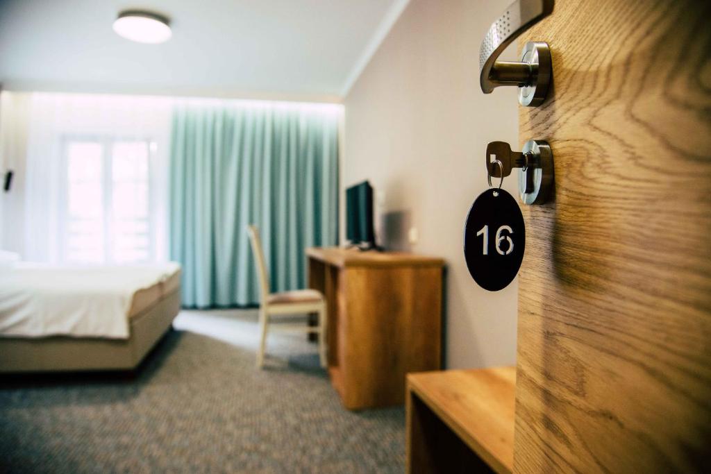 Wrzosowa في Kamieńsk: غرفة فندق مع غرفة نوم مع سرير وباب