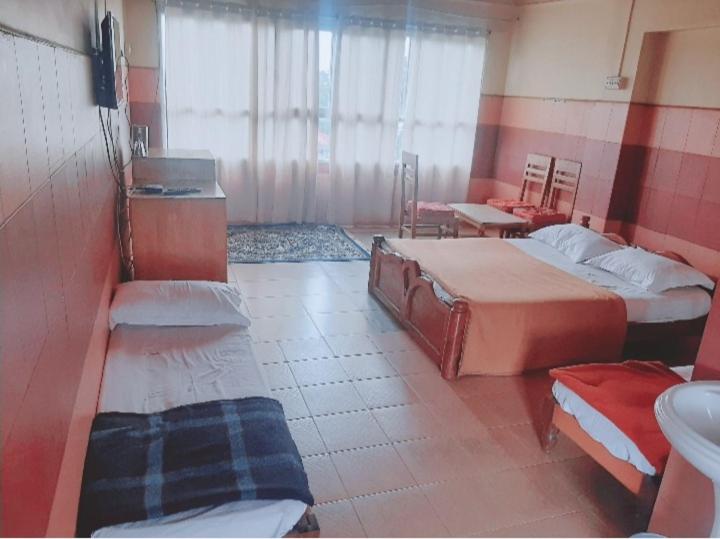 Habitación con 2 camas y baño con lavabo. en Vega Residency en Madikeri