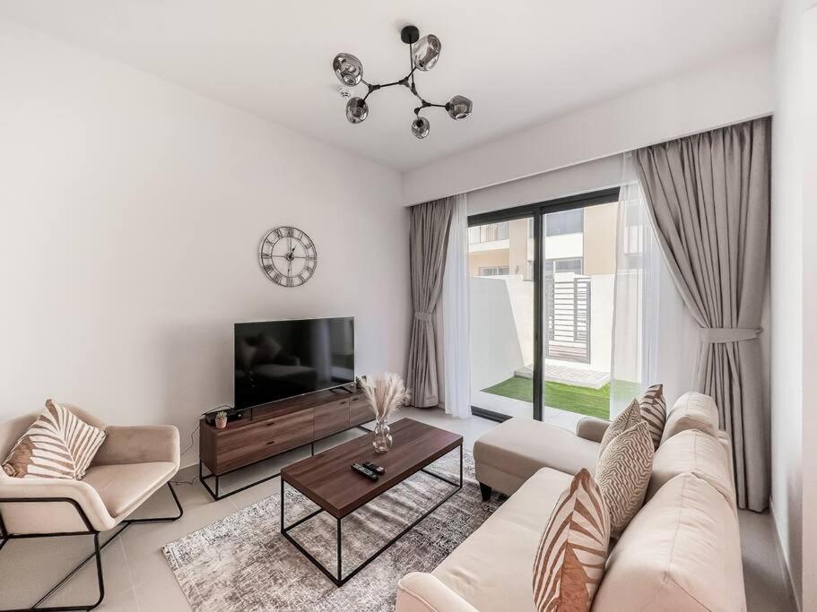ein Wohnzimmer mit einem Sofa und einem TV in der Unterkunft StoneTree - 3 BR with 1 Maids Room Villa in Camelia - Arabian Ranches in Dubai