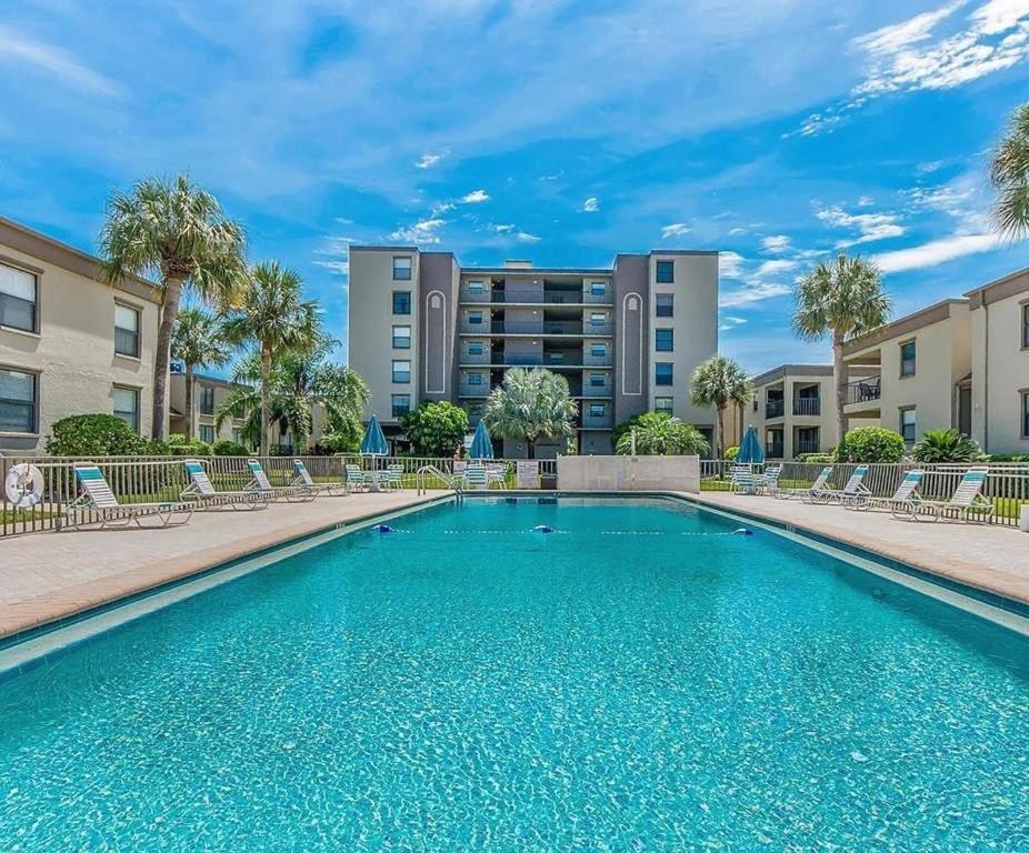 a swimming pool with chairs in front of a building at Sea Club Condo #405 in Clearwater Beach
