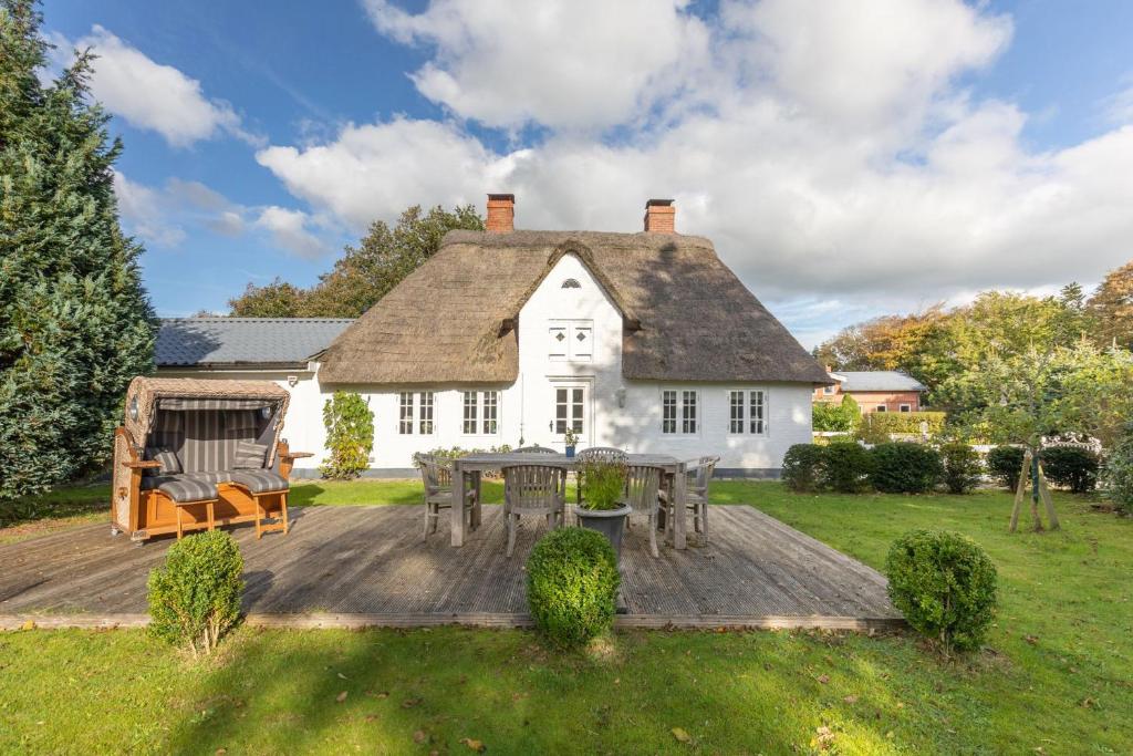 a white house with a wooden deck in the yard at Das Countryhouse in Humptrup