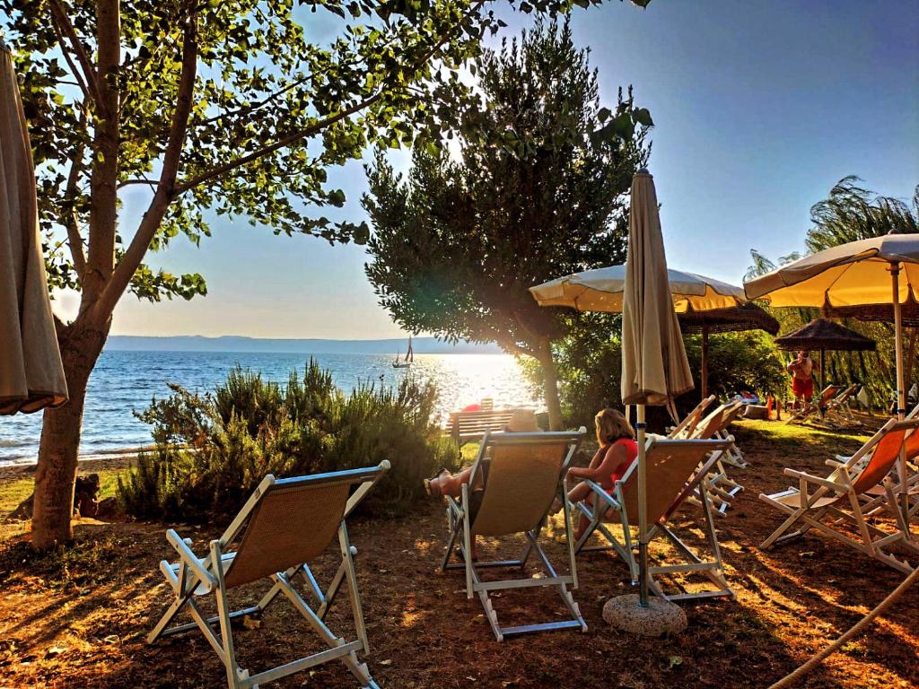 un grupo de personas sentadas en sillas en la playa en International Glamping Lago Di Bracciano, en Trevignano Romano