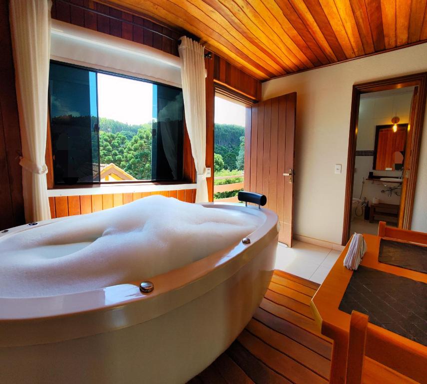 a large bath tub in a room with a window at Chalés Leopoldo em Monte Verde in Monte Verde
