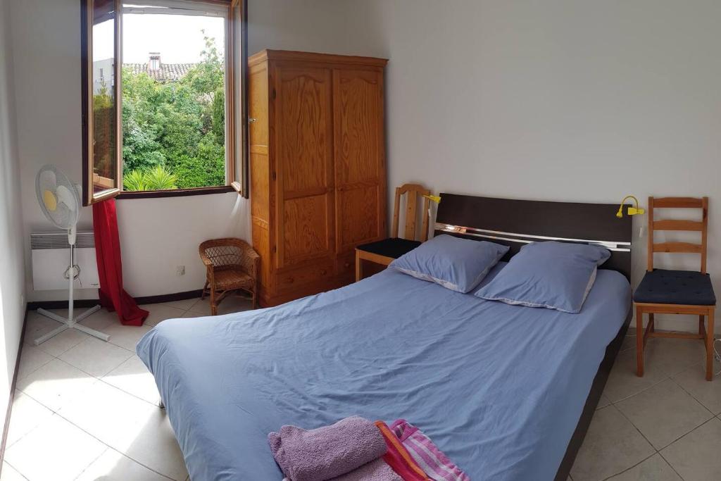 a bedroom with a bed with blue sheets and a window at Petit Paradis au calme en plein Marseille in Marseille