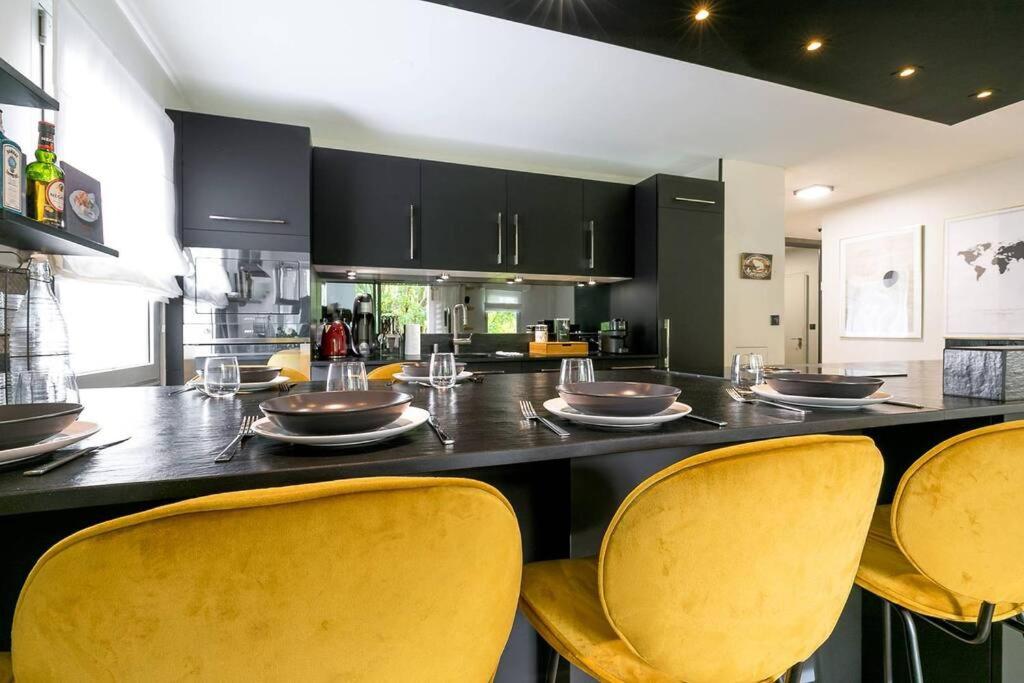 une cuisine avec un bar avec des chaises jaunes et un comptoir dans l'établissement Jardin Wilson, à Dijon