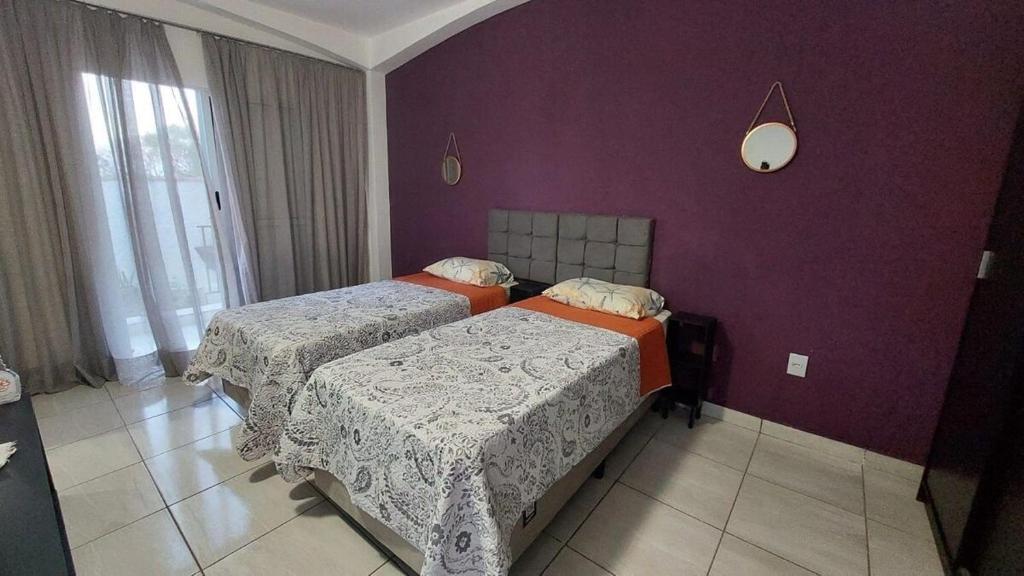 1 dormitorio con 2 camas y pared púrpura en Estúdios Jardim Emília, en Sorocaba