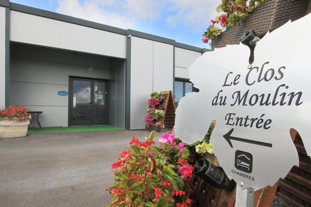 a sign in front of a building with flowers at Le Clos du Moulin in Vaudemanges