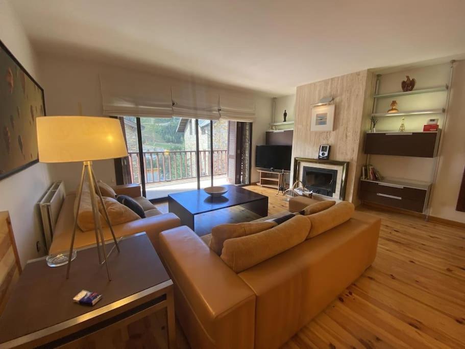 uma sala de estar com um sofá castanho e uma lareira em P&C Quatre Vents - Tarter em El Tarter