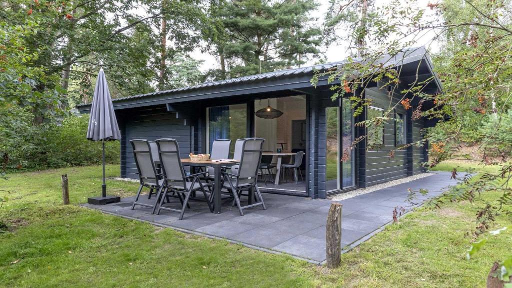 a black cabin with a table and chairs and an umbrella at Molecaten Park Landgoed Ginkelduin in Leersum