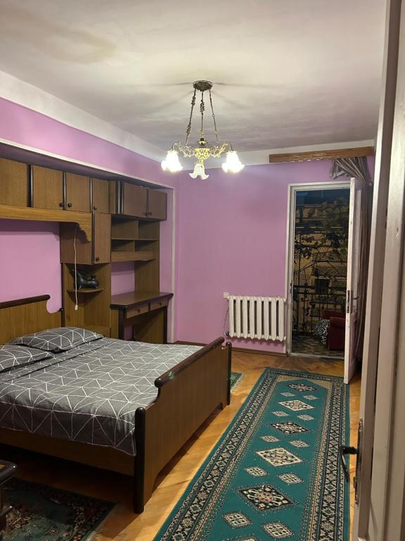 um quarto com uma cama, paredes roxas e um lustre em Mtatsminda Apartment Best View em Tbilisi
