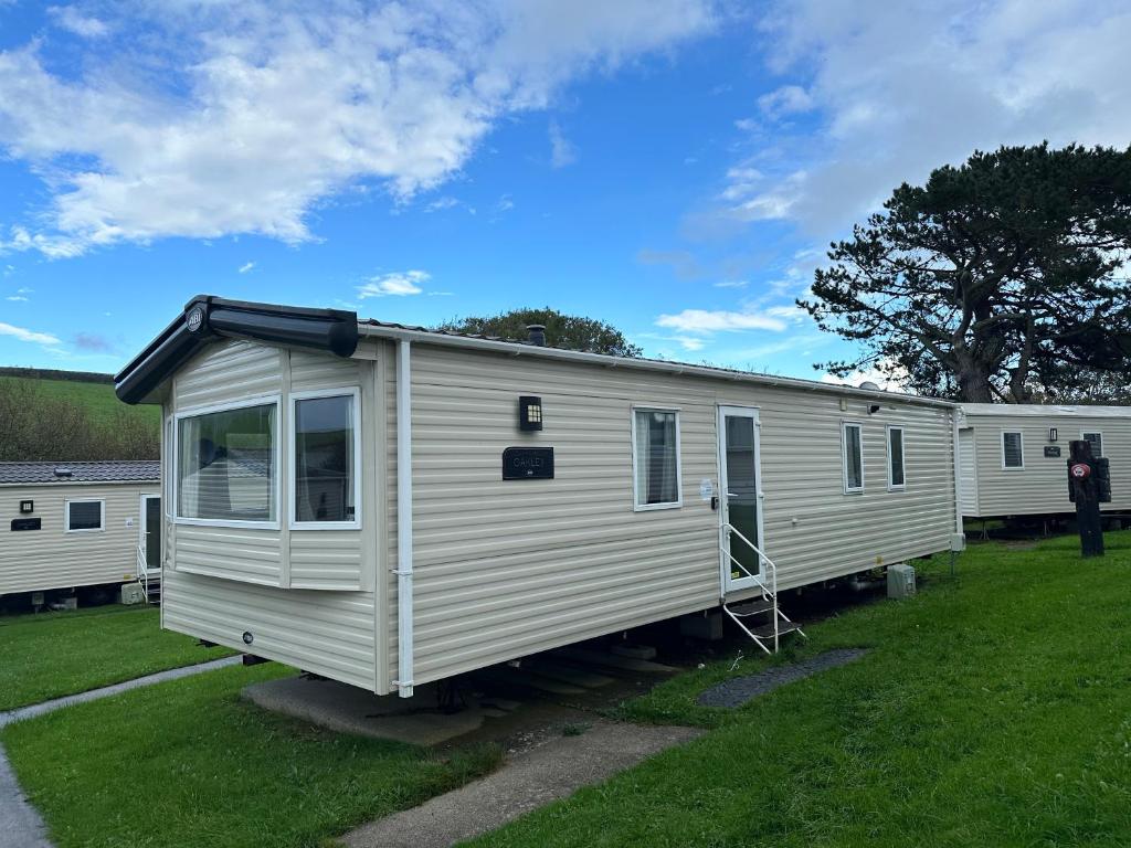a white mobile home parked in a yard at Newquay Bay Porth Caravan - 6 berth in Newquay