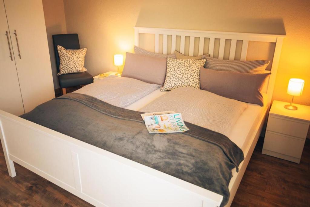 a large white bed with a book on top of it at Haus Jelena Appartement 1 in Borkum