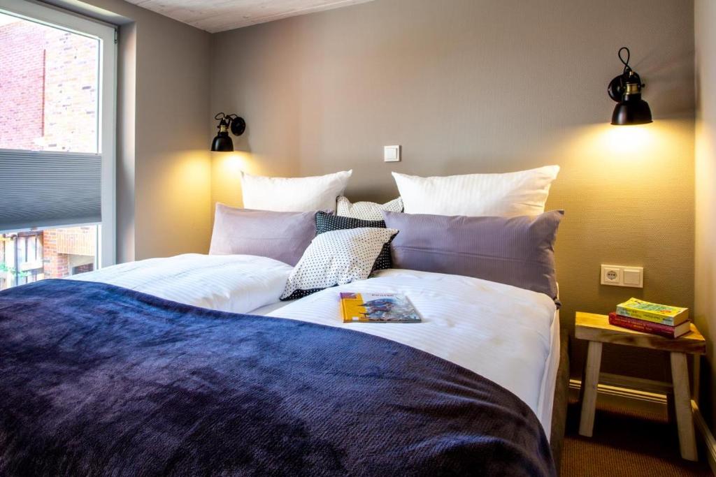 1 dormitorio con 2 camas y almohadas blancas en Logierhaus K15 Appartement 2 Plus en Borkum