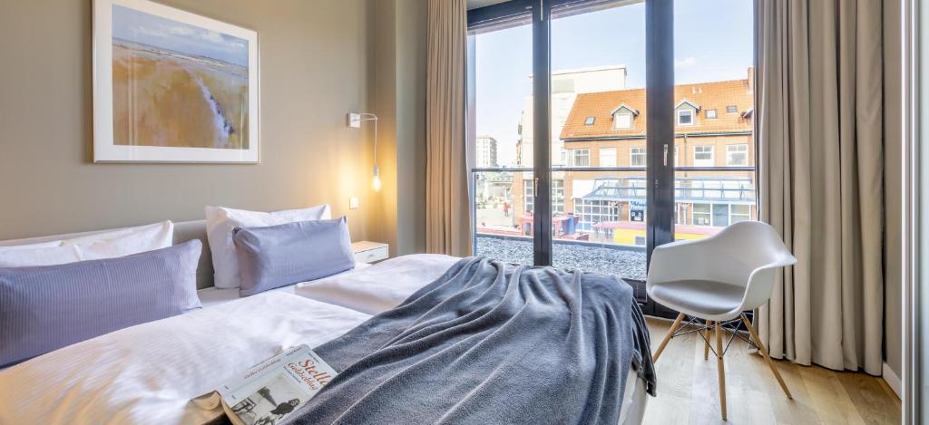 a bedroom with a bed and a chair and a window at Sparkassengebäude Wohnung 2 in Borkum