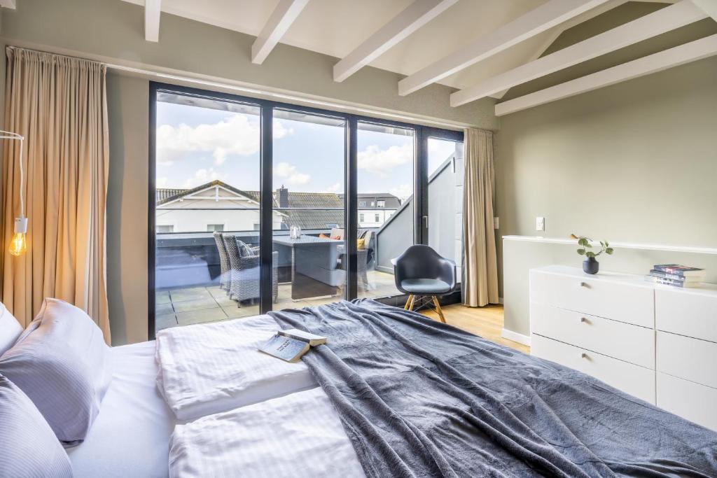 een slaapkamer met een bed en een groot raam bij InselLoft Wohnung 4 in Borkum