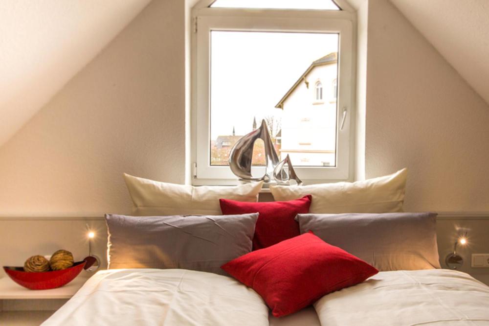 a bed with red and white pillows and a window at Haus Stranddüne in Borkum