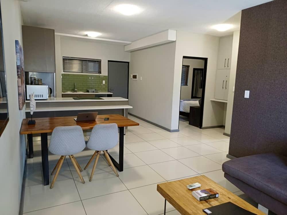 a kitchen and living room with a table and chairs at MERENSKY Windhoek in Windhoek