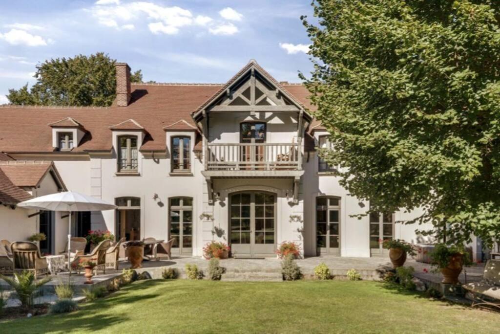 a house with a balcony on the front of it at Propriété de charme avec SPA au cœur de Barbizon.La Barbizonaise in Barbizon