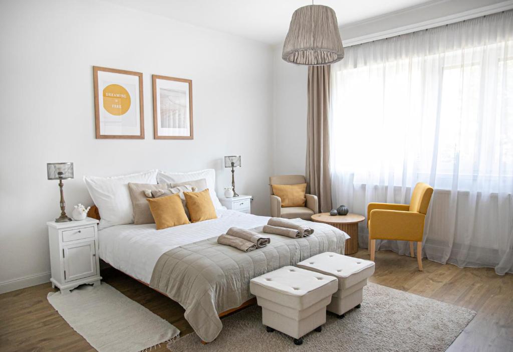 una camera bianca con un grande letto e una sedia di Cozy Airport a Vecsés
