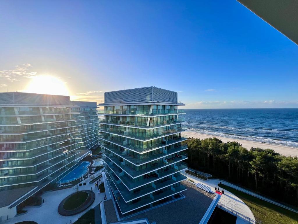 a large building next to the beach with the ocean at Wave Sea View in Międzyzdroje