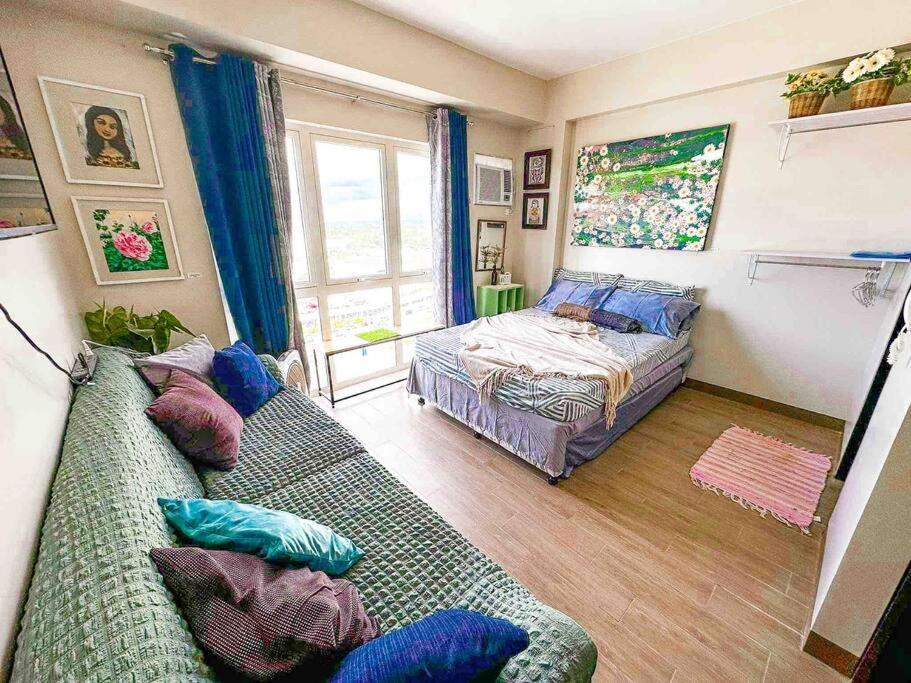 a living room with a couch and a bed at Staycation @ UpperEast w/ Pool, Gym, Daycare etc.! in Bacolod