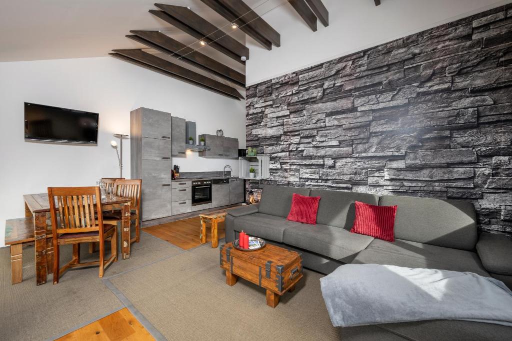 salon z kanapą i kamienną ścianą w obiekcie Berg&Selig Apartment w mieście Pfarrwerfen