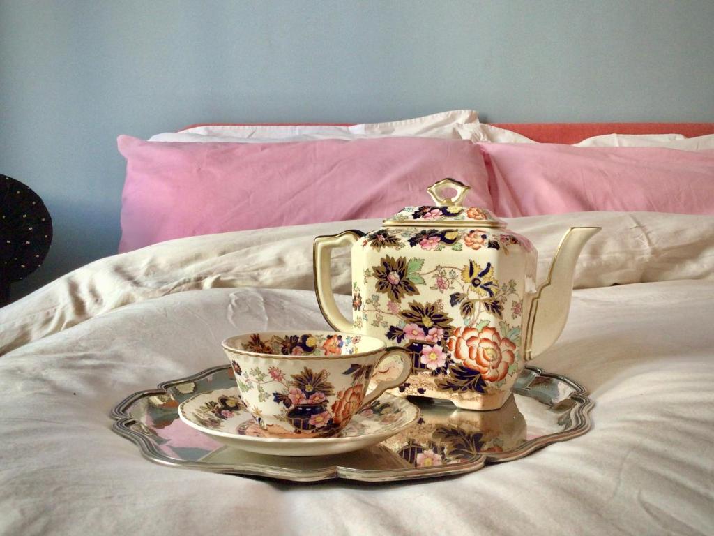 a tea pot and a cup on a bed at Just one room in Rome