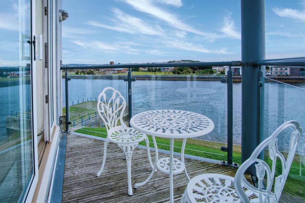 a balcony with a table and chairs and a view of the water at The Penthouse - 3 Bedroom Apartment - Llanelli in Llanelli