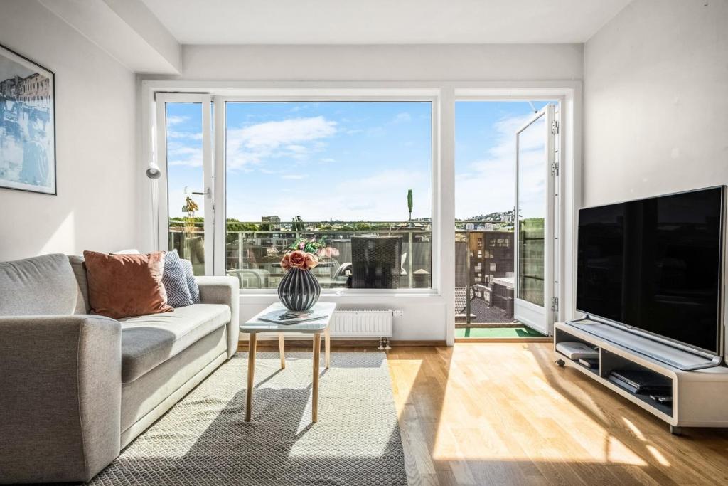 sala de estar con sofá y ventana grande en Lovely central flat with great view, en Oslo