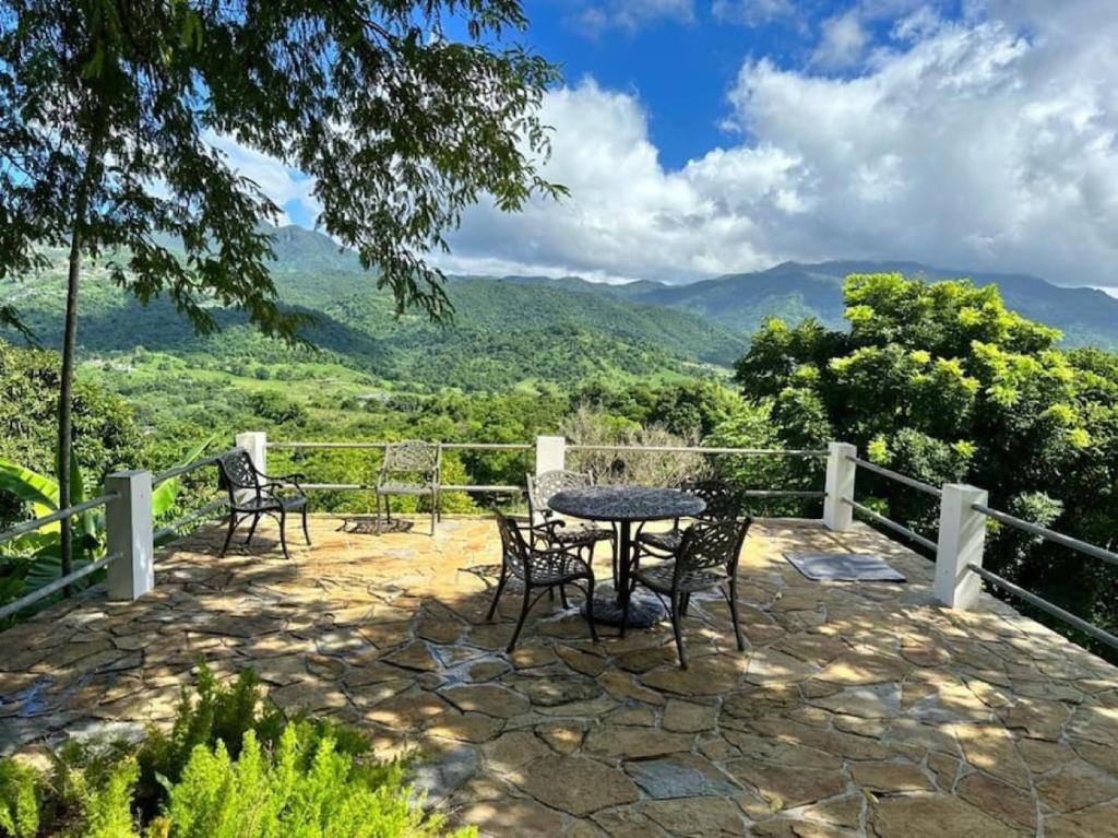 a patio with a table and chairs and mountains at KASA Finca La Limonada near Palmas Del Mar in Humacao
