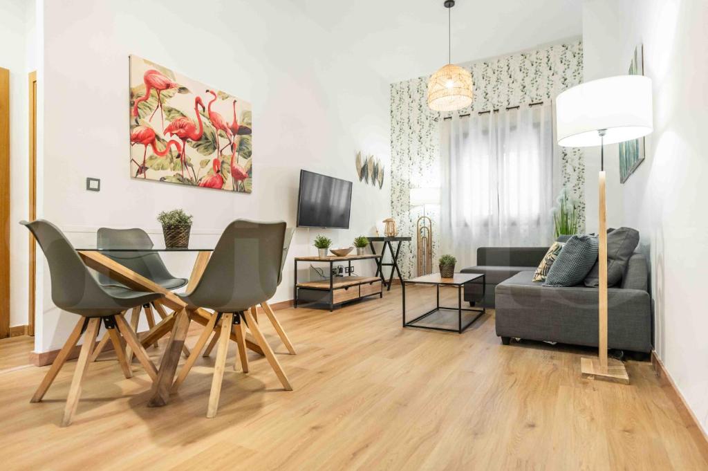 a living room with a table and chairs and a couch at 3BR apartment with community pool, parking and patio - Center by REMS in Málaga