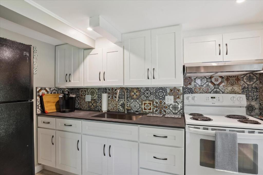 a kitchen with white cabinets and a black refrigerator at Stowe Gallery Apartment in Stowe