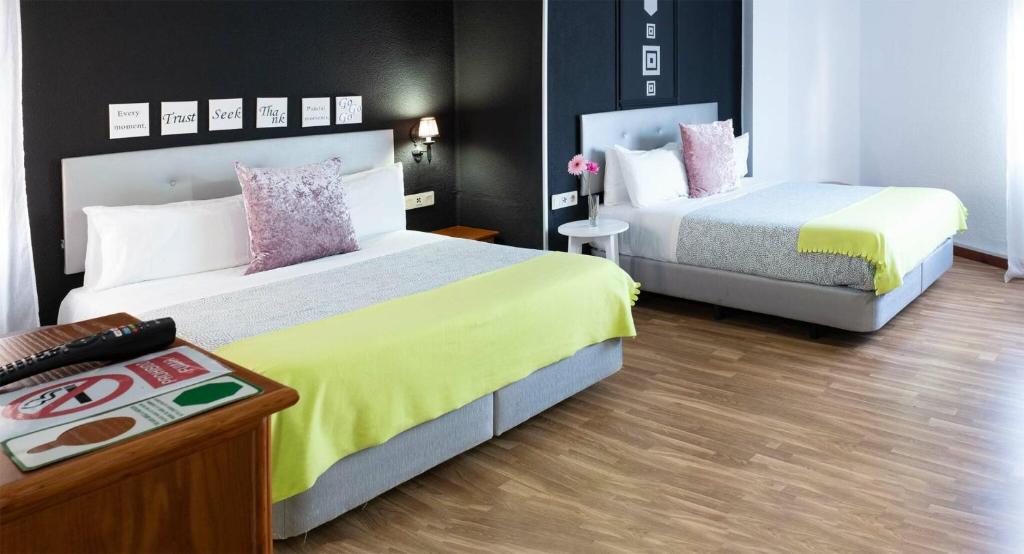 una habitación de hotel con dos camas y una mesa en Hostal Victoria, en Altura