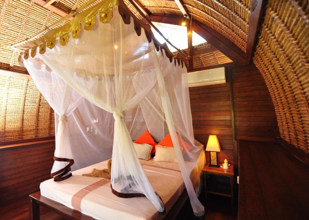 a bedroom with a canopy bed with white curtains at brothers bungalows in Jimbaran