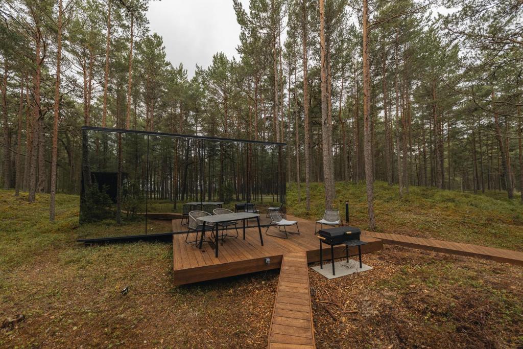 a pavilion with a table and chairs in a forest at ÖÖD Hötels Lohusalu LEIDA & ENNO in Laulasmaa