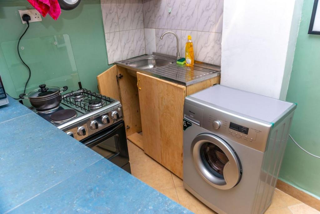 a kitchen with a stove and a washing machine at Meraki home 3 in Kampala