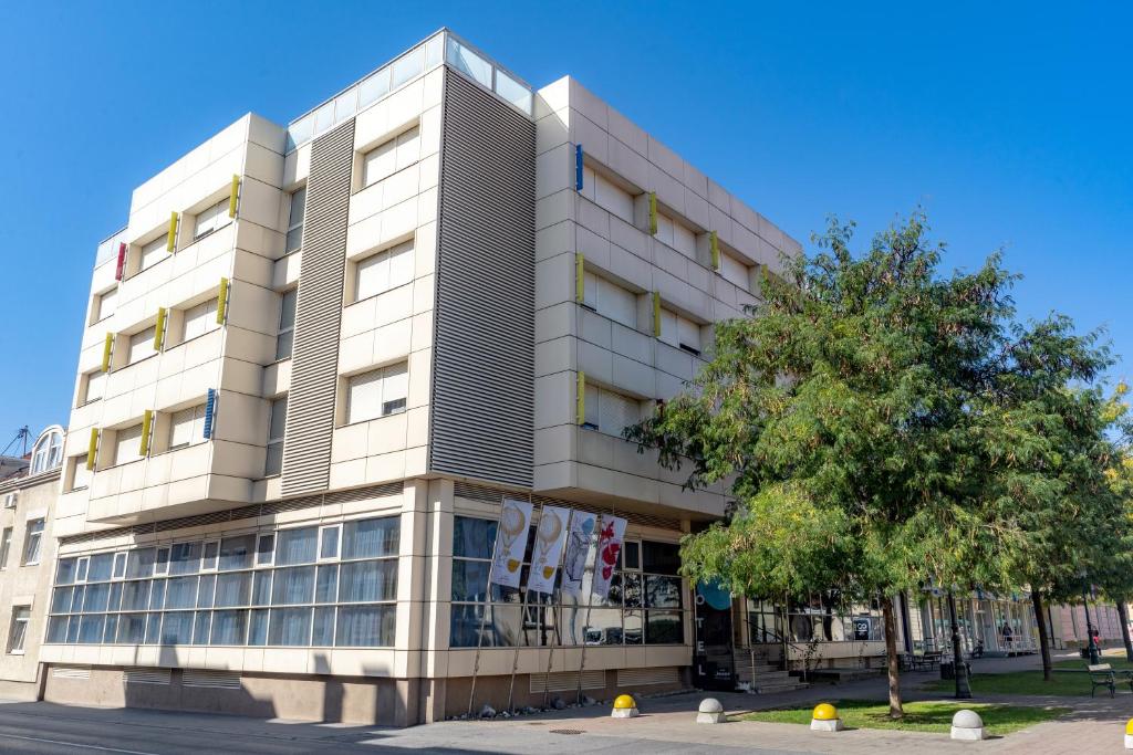 un gran edificio con un árbol delante en Artearia Hotel, en Bjelovar