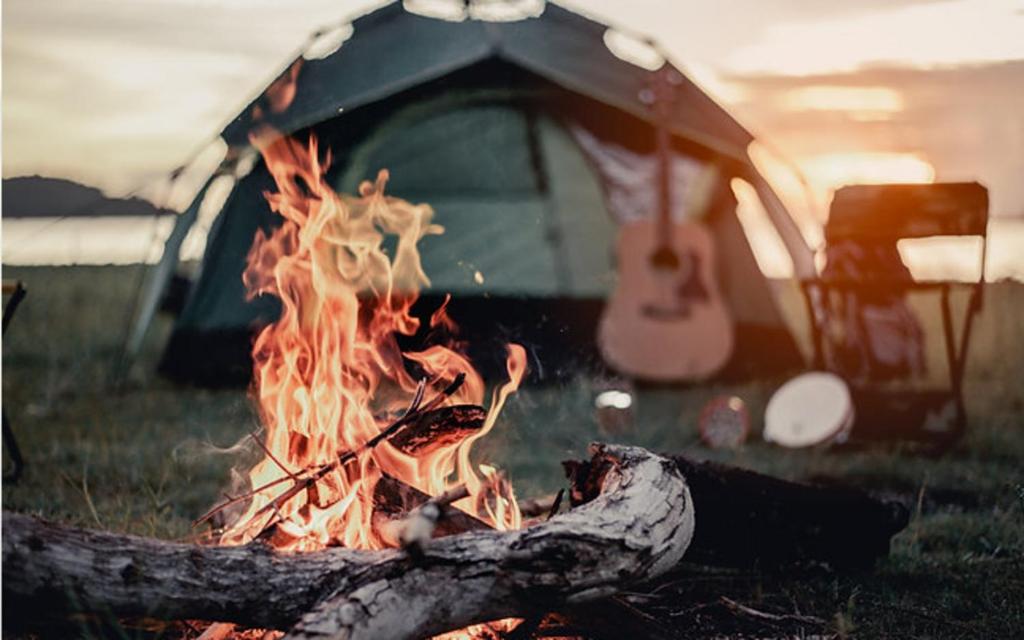 a camp fire in front of a tent with a guitar at Glamping Calvados 
