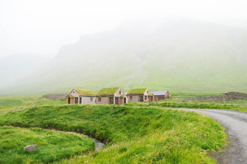 a group of houses on a hill next to a road at Múlafossur Cottages by famous waterfall in Gásadalur in Gásadalur