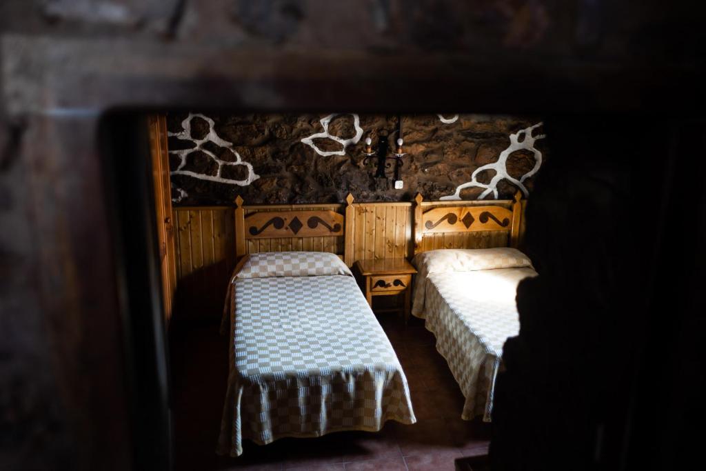 a room with two beds in a room with a wall at Casa de Aldea Menéndez in Cangas del Narcea
